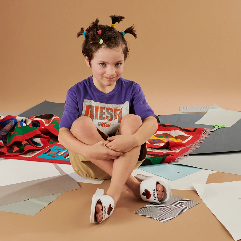 A boy sitting down and wearing a stylish summer look