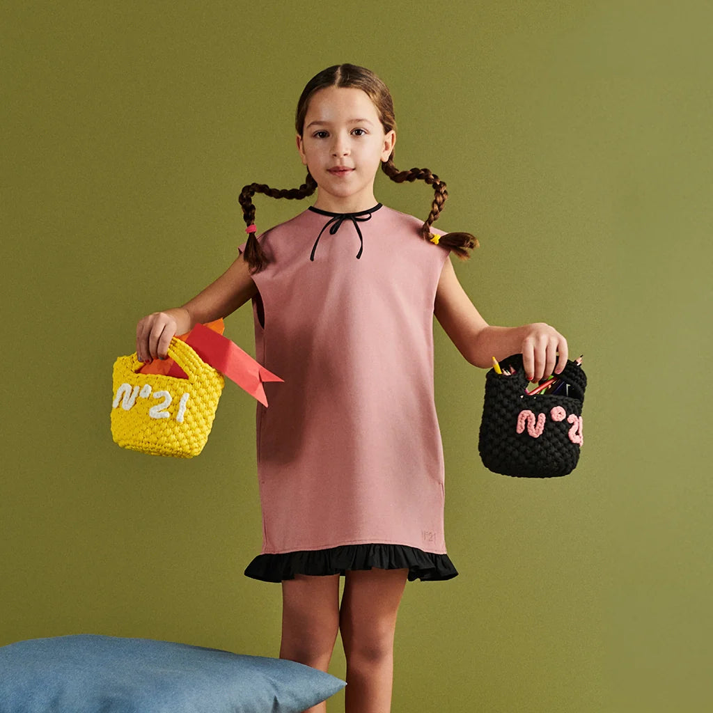 A girl with a pink dress, holding two stylish summer bags